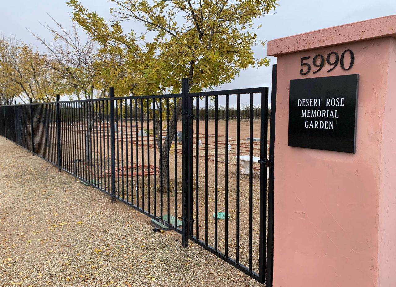 A view along the iron fence, through the gravesites are visible.