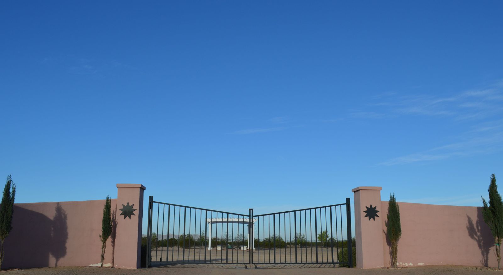 The stucco walls and iron gates of the Memorial Garden stand sentinel under a clear blue sky.